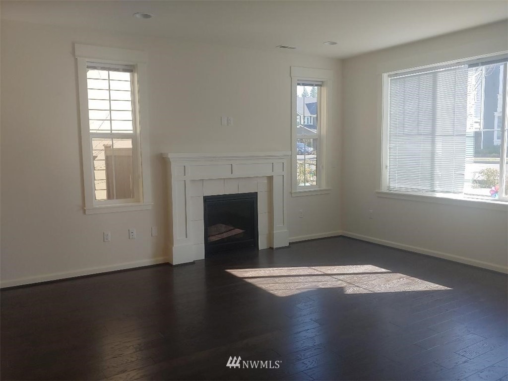 4422 185th Place Southeast Bothell, WA 98012 - Photo 8 of 28 an empty room with wooden floor fireplace and windows