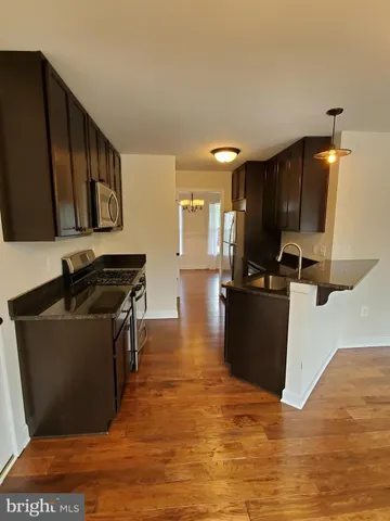 a kitchen with stainless steel appliances granite countertop a refrigerator a stove top oven and a sink