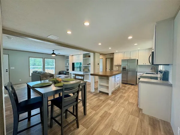 a kitchen with stainless steel appliances kitchen island granite countertop a table chairs sink and cabinets