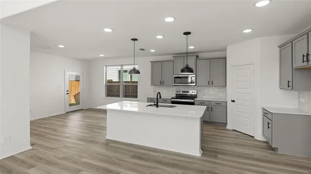 a kitchen with stainless steel appliances kitchen island granite countertop a stove top oven a sink and a refrigerator