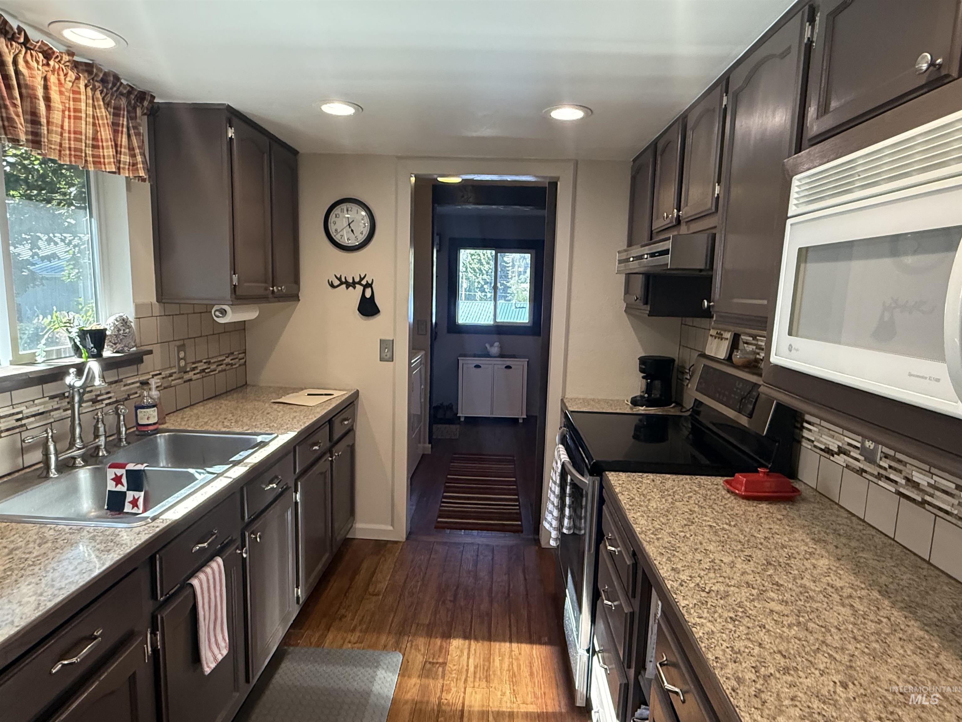 403 138th Street Orofino, ID 83544 - Photo 7 of 32 Kitchen featuring stainless steel electric range oven, white microwave, under cabinet range hood, tasteful backsplash, and dark wood-style floors