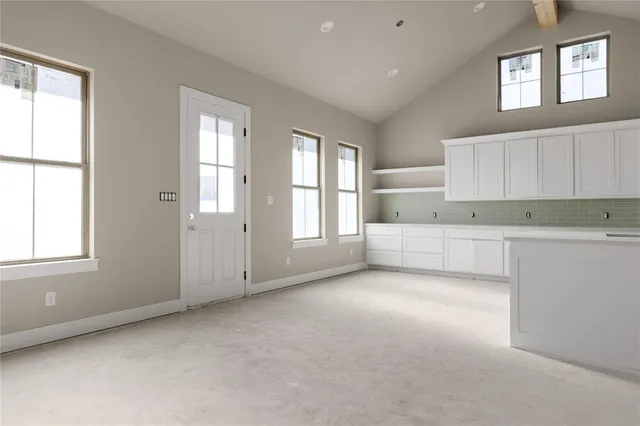 an empty room with chandelier fan and windows