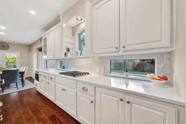a large white kitchen with wooden floor and stainless steel appliances