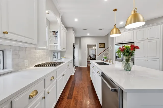 a view of a kitchen with stainless steel appliances kitchen island wooden floors and white cabinets