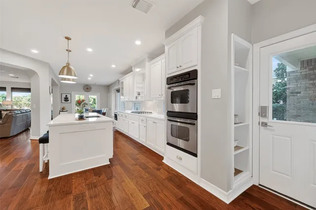 a large white kitchen with stainless steel appliances and wooden floor