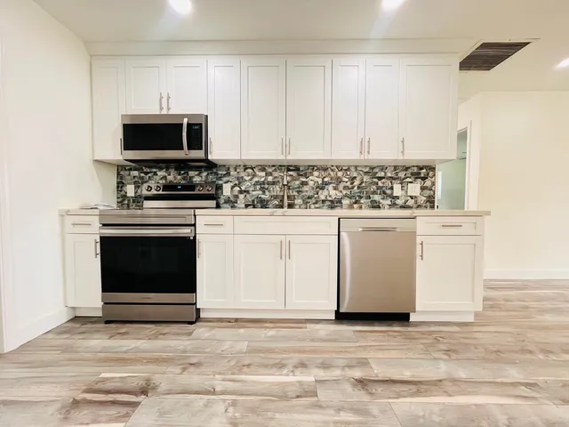 a kitchen with white cabinets and oven