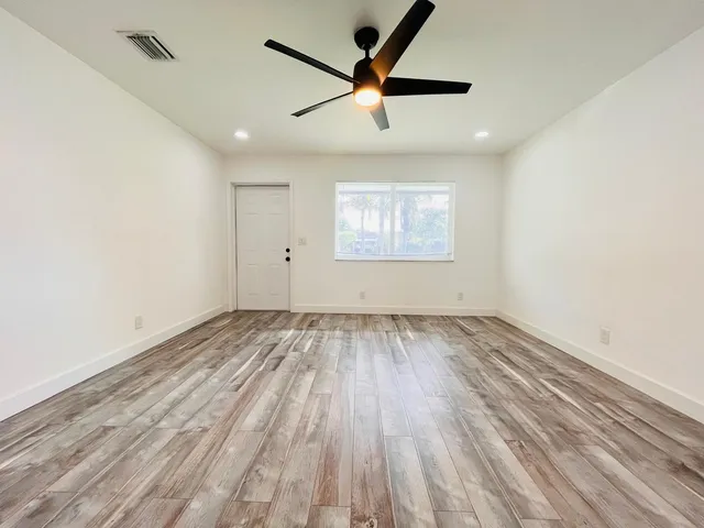an empty room with wooden floor and windows