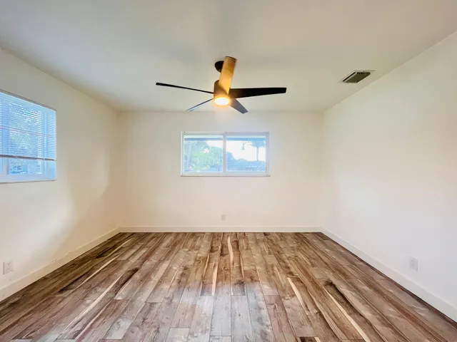 a view of a room with wooden floor a ceiling fan and window