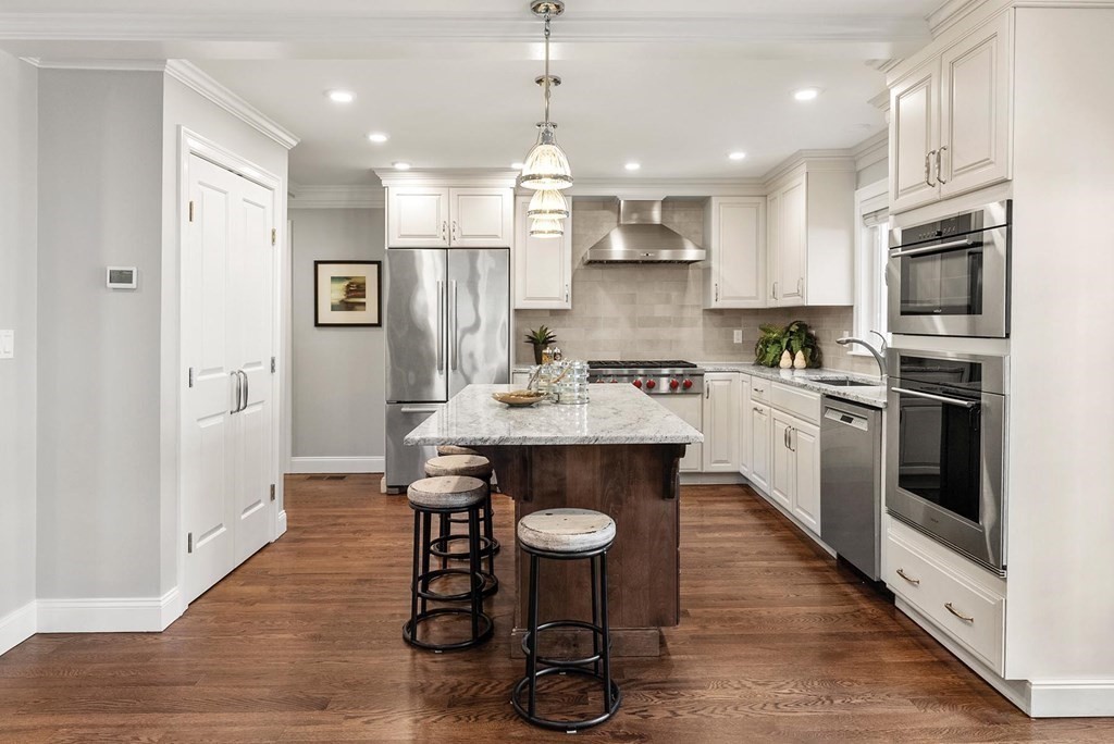 77 Beaconsfield Road, Unit 77 Brookline, MA 02445 - Photo 6 of 21 a kitchen with stainless steel appliances a dining table chairs stove refrigerator and cabinets