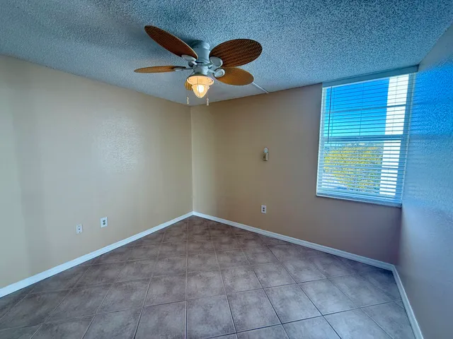 an empty room with windows and fan