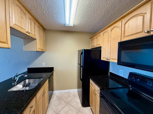 a kitchen with granite countertop stainless steel appliances a stove refrigerator a sink and a microwave