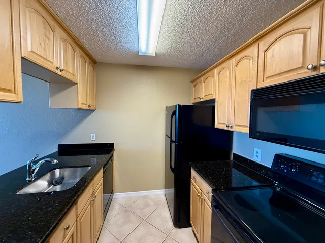 a kitchen with granite countertop stainless steel appliances a stove refrigerator a sink and a microwave