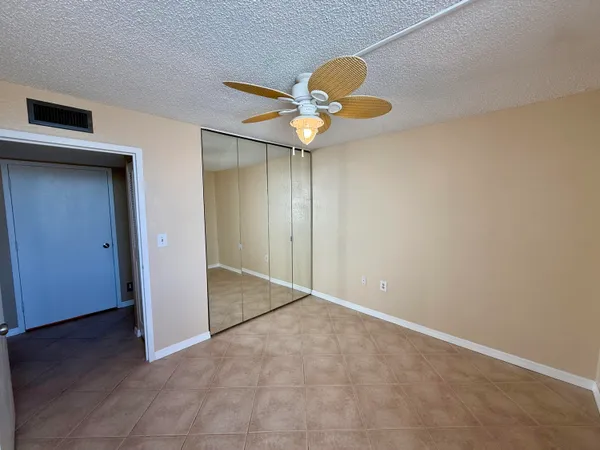 an empty room with closet and a chandelier fan
