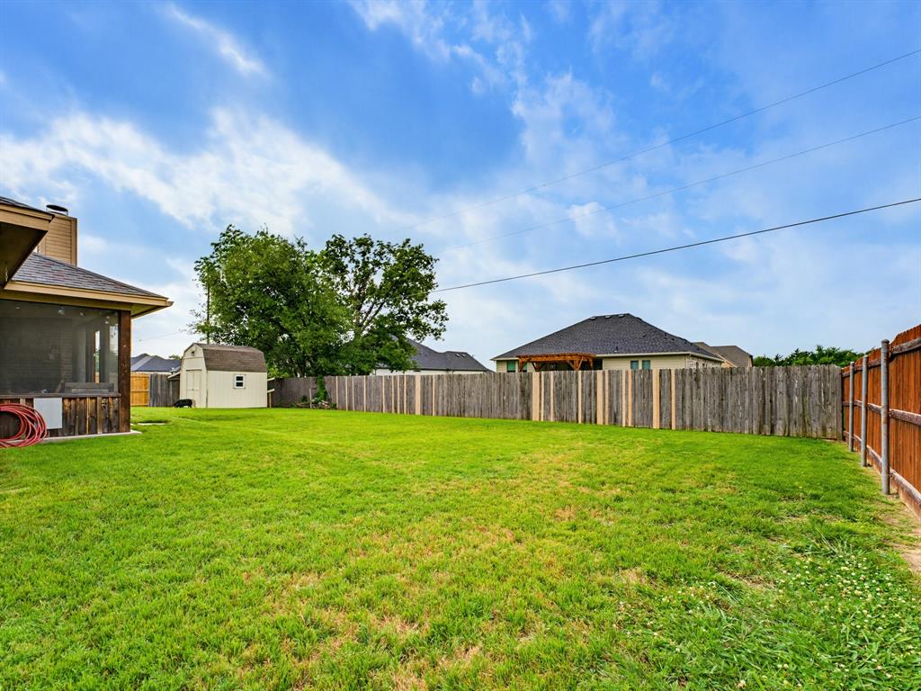 2108 Ridgewood Drive Bridgeport, TX 76426 - Photo 34 of 35 Expansive green lawn featuring a screened patio, a detached storage shed, and perimeter wood fencing