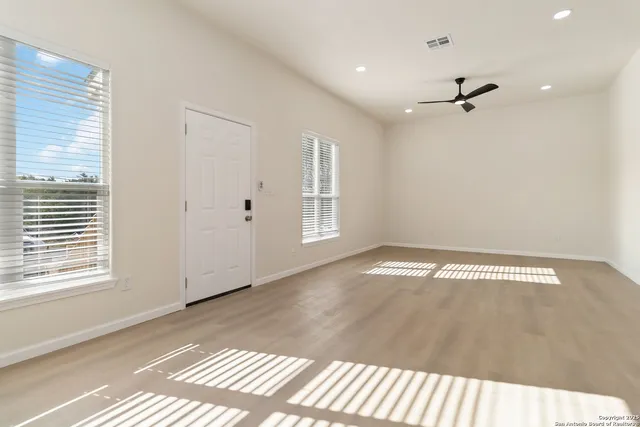 a view of empty room with wooden floor and fan