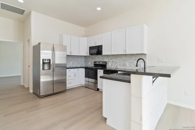 a kitchen with granite countertop a refrigerator and a stove top oven