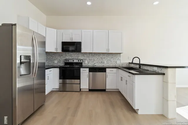 a kitchen with stainless steel appliances granite countertop a refrigerator and a stove top oven