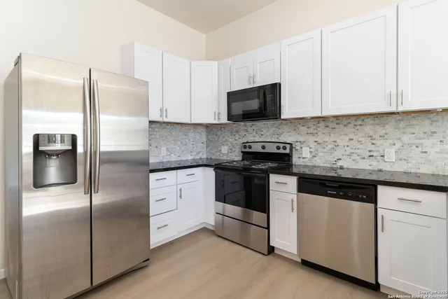 a kitchen with stainless steel appliances granite countertop a refrigerator a stove a sink and a microwave