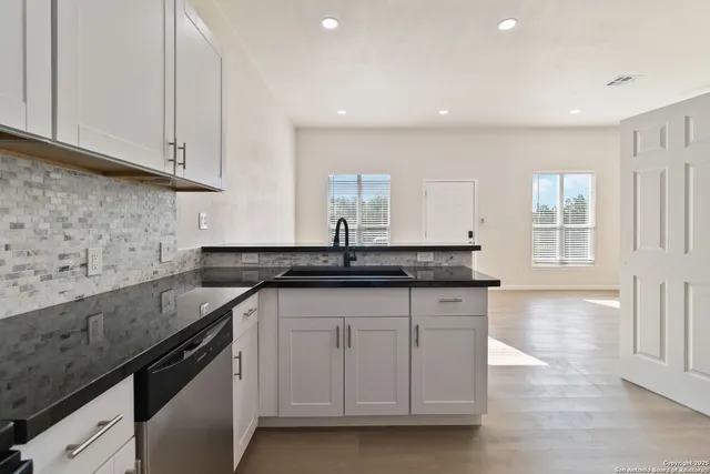 a kitchen with granite countertop a sink white cabinets and a granite counter tops