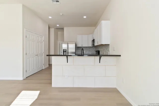 a view of kitchen with granite countertop white cabinets and stainless steel appliances