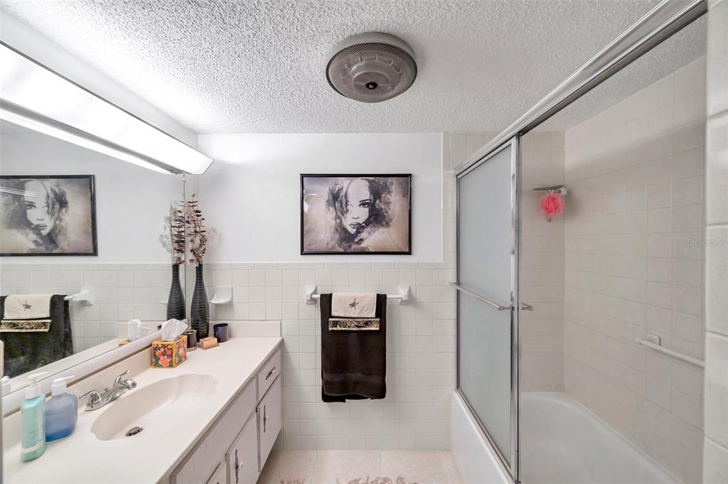 1430 Heather Ridge Boulevard, Unit 304 Dunedin, FL 34698 - Photo 21 of 36 a bathroom with a sink a mirror and a shower