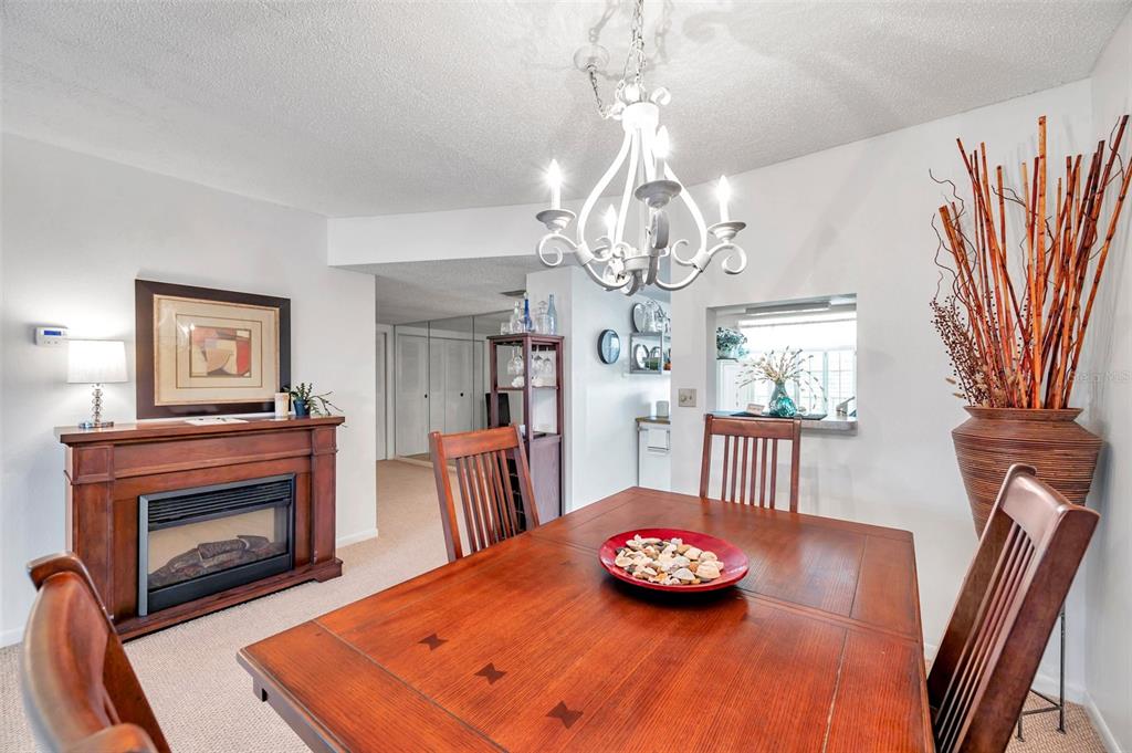 1430 Heather Ridge Boulevard, Unit 304 Dunedin, FL 34698 - Photo 6 of 36 a living room with dining table and a fireplace