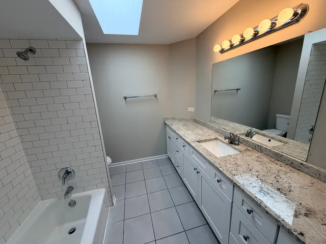 a bathroom with a granite countertop sink a toilet and bathtub