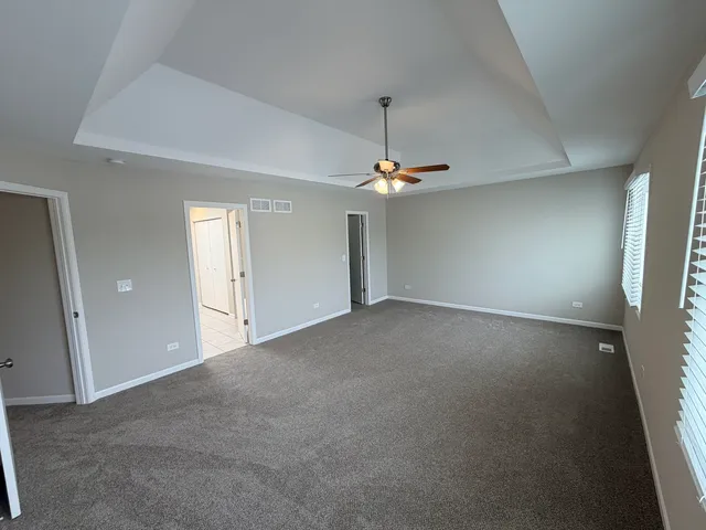a view of an empty room with chandelier fan