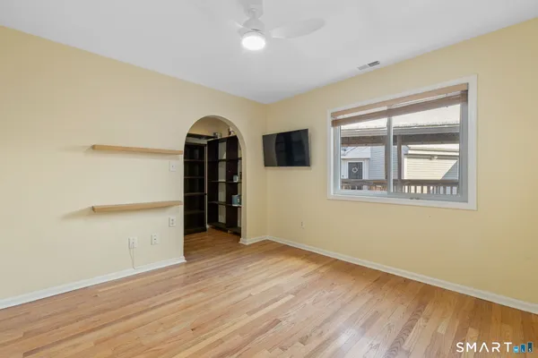 a view of empty room with wooden floor and fan