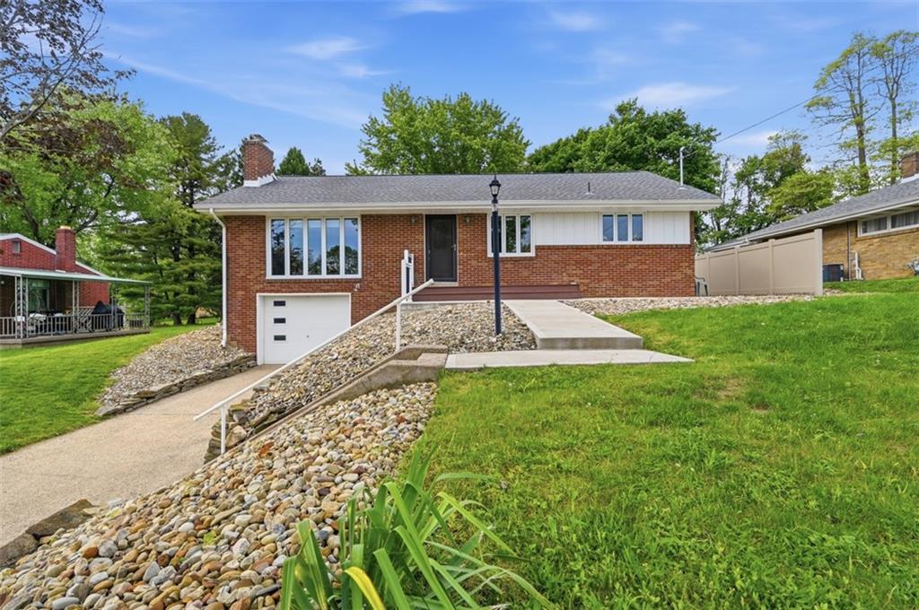 a front view of house with yard and trees in the background