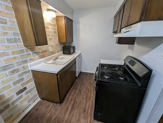 a kitchen with stainless steel appliances granite countertop a stove a sink and a microwave