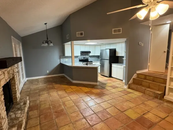 a view of a kitchen with kitchen island granite countertop a refrigerator and a stove top oven