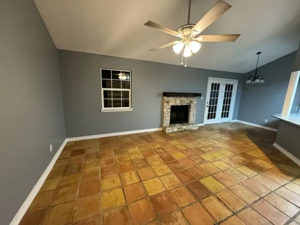 a view of an empty room with a chandelier fan and a window