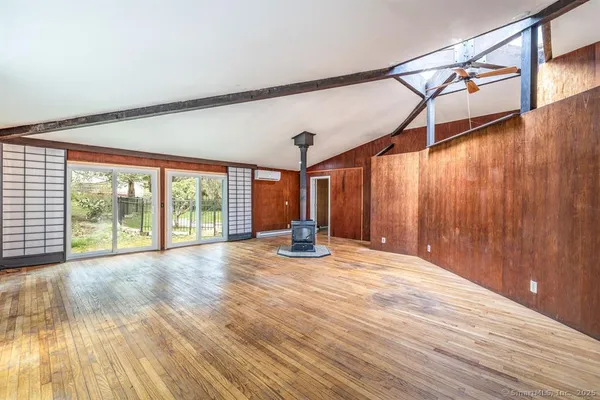 a view of an empty room with wooden floor and a large window