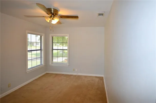 an empty room with windows and fan