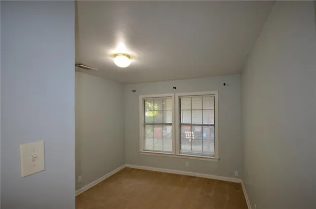 an empty room with chandelier fan and windows