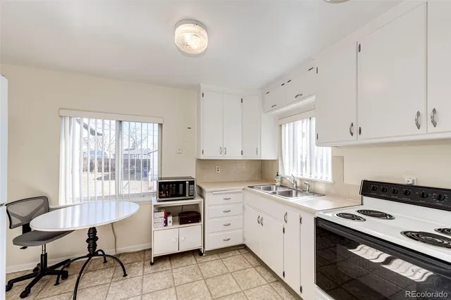 a kitchen with a stove a sink and white cabinets
