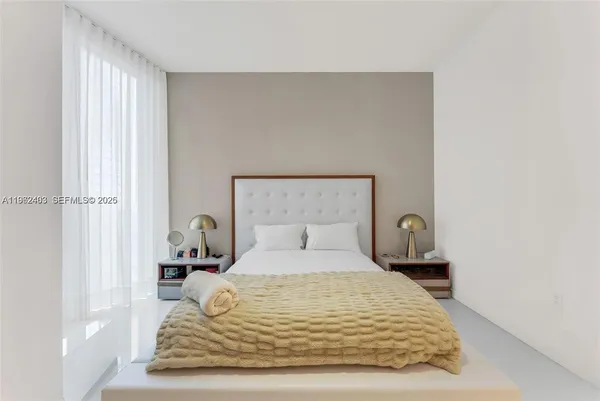 a bedroom with a bed and a lamp on dresser