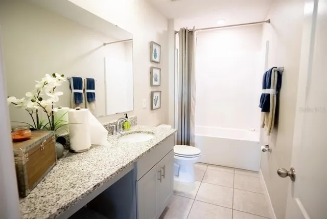 a bathroom with a granite countertop sink a toilet and shower