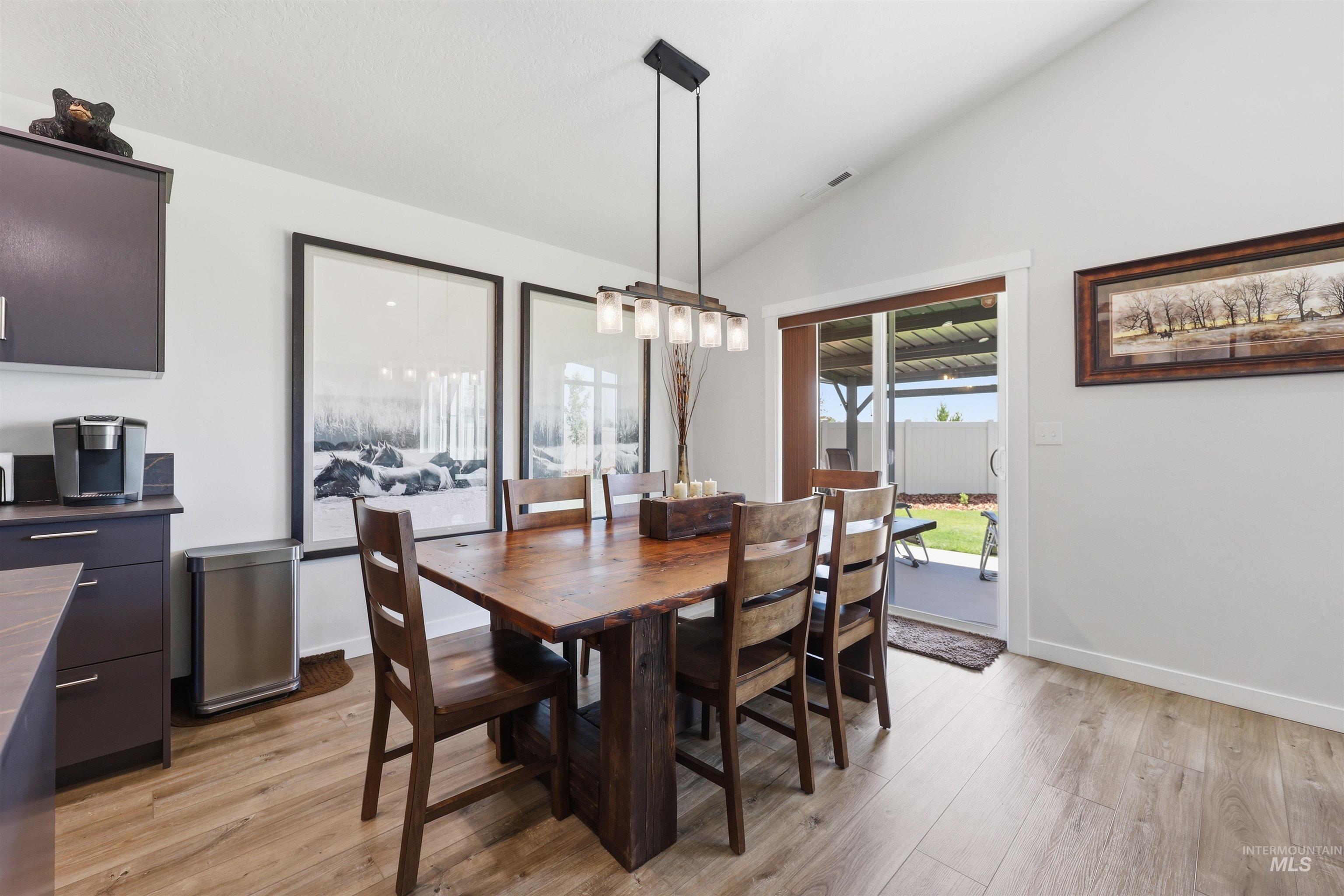 3811 West Maypearl Street Meridian, ID 83642 - Photo 22 of 39 Dining area with vaulted ceilings, wood-finish flooring, and a contemporary linear chandelier