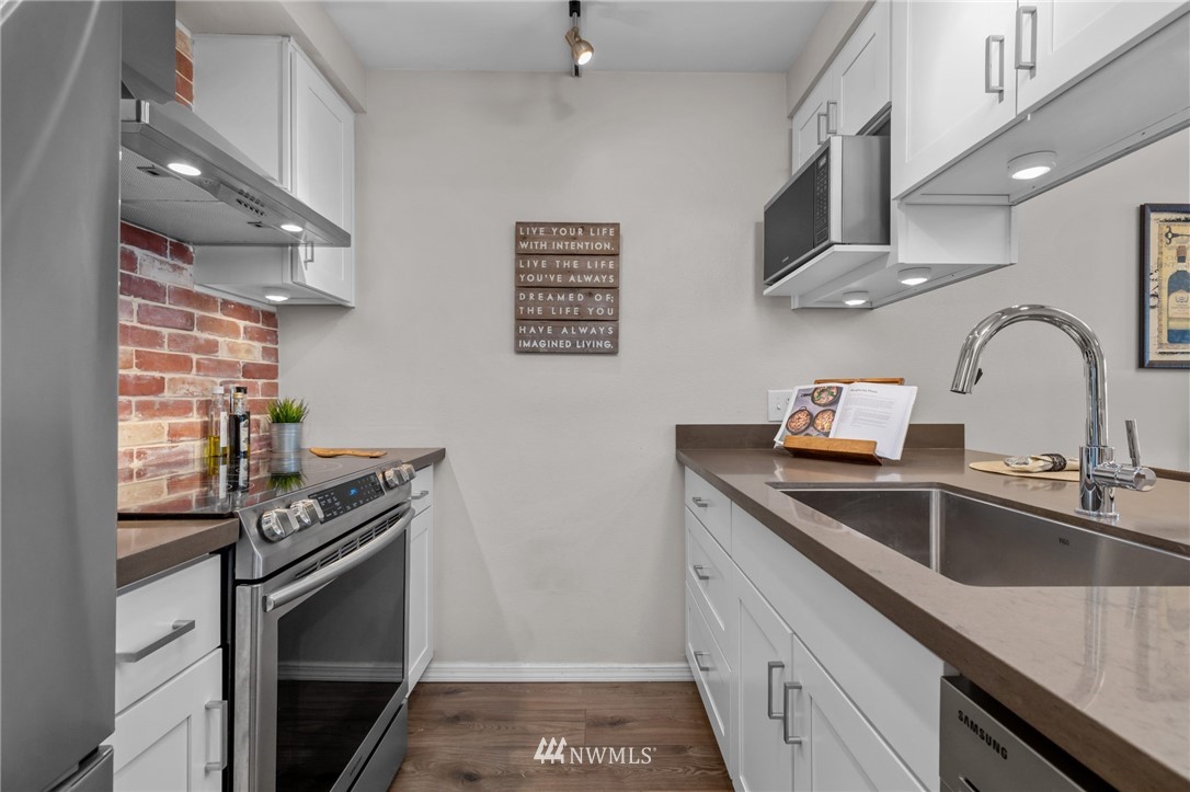769 Hayes Street, Unit 609 Seattle, WA 98109 - Photo 10 of 26 a kitchen with stainless steel appliances granite countertop a sink stove and cabinets