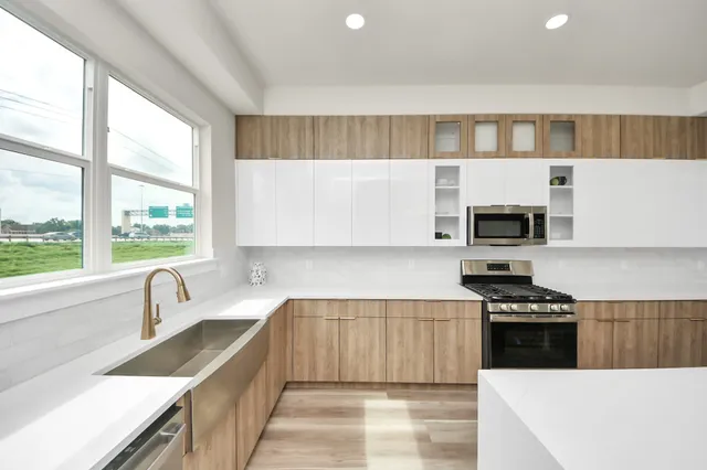 a kitchen with stainless steel appliances a sink a stove a microwave and white cabinets