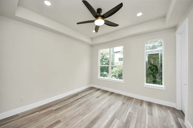 an empty room with wooden floor and windows