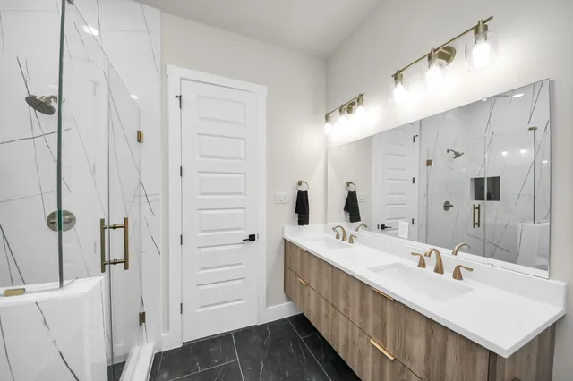 a bathroom with a double vanity sink mirror and shower