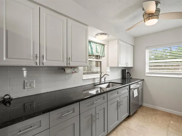 a kitchen with granite countertop a sink stainless steel appliances white cabinets and a window
