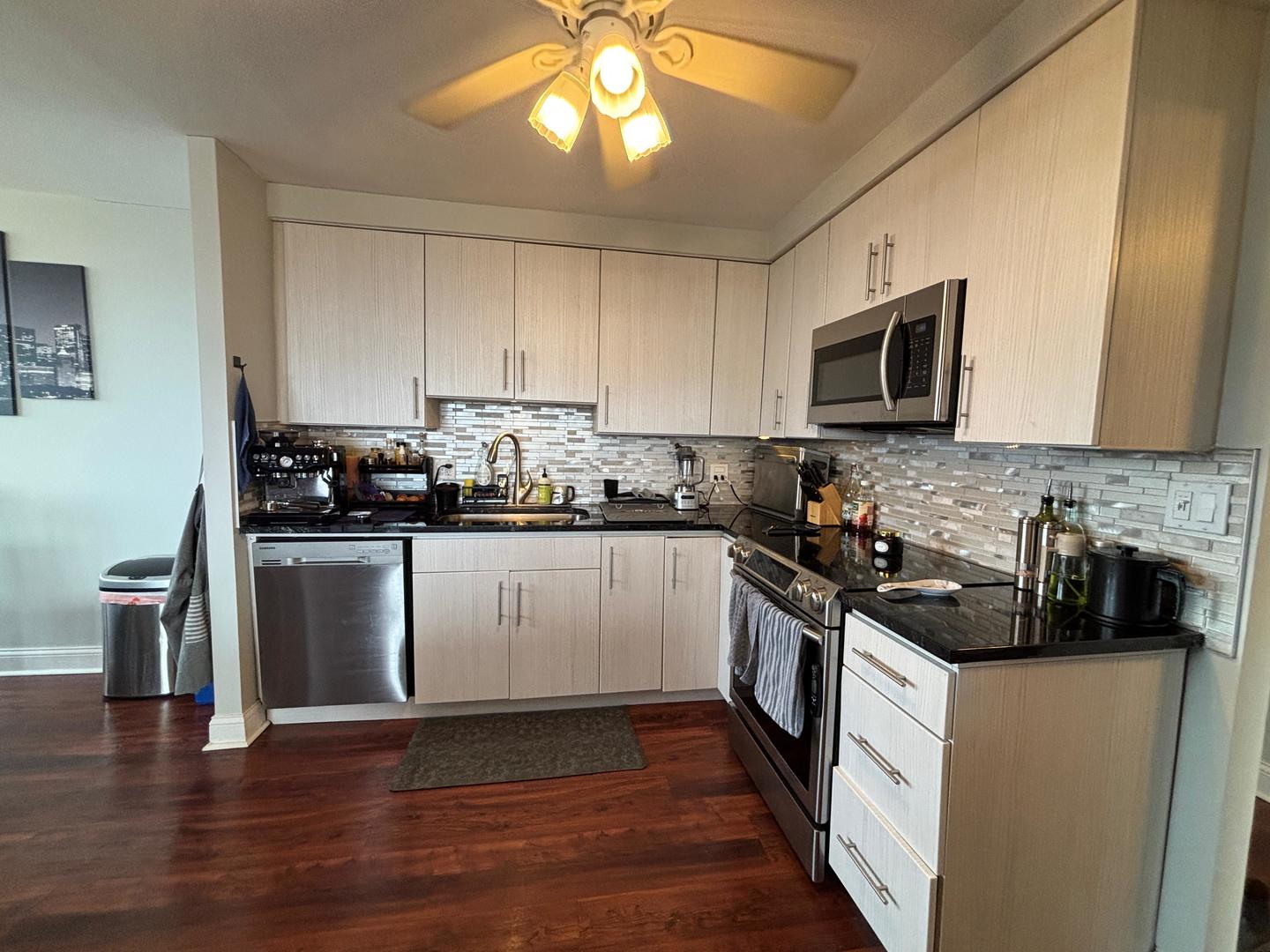 101 Bar Harbour Road, Unit 6M Schaumburg, IL 60193 - Photo 13 of 29 a kitchen with stainless steel appliances granite countertop a stove a sink dishwasher and a microwave oven with wooden floor