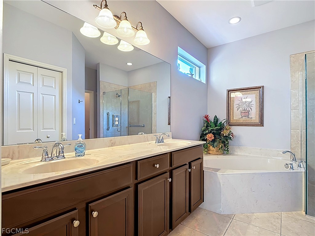 20763 Athenian Lane North Fort Myers, FL 33917 - Photo 31 of 49 a bathroom with a granite countertop sink a large mirror and a bathtub