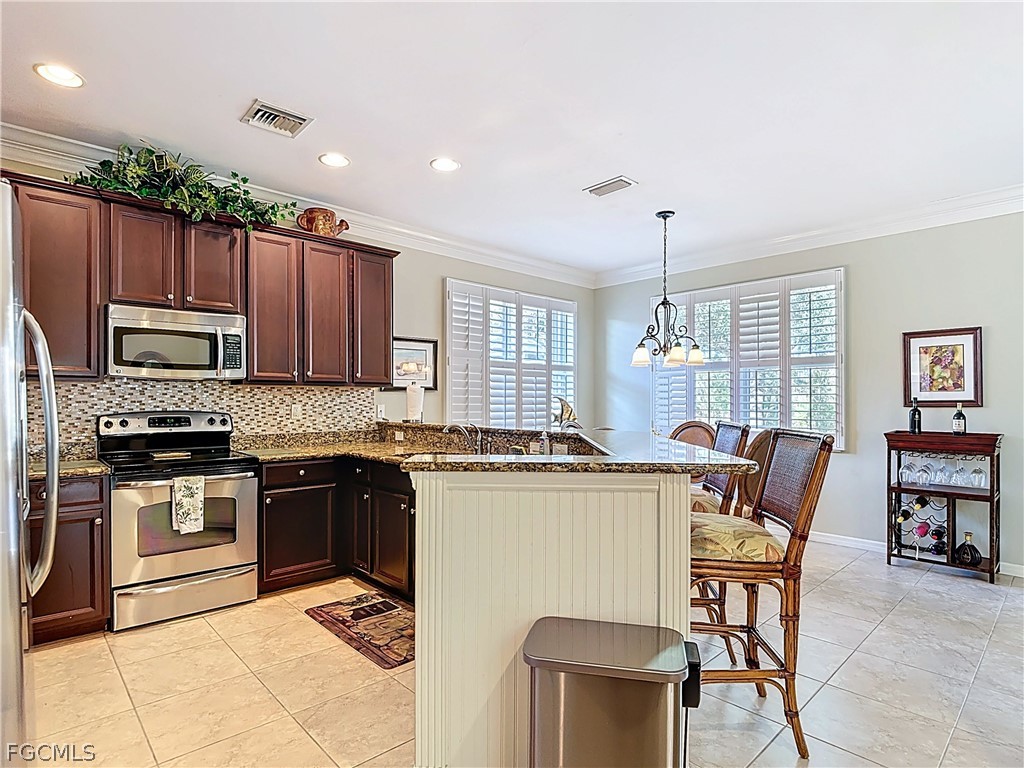 20763 Athenian Lane North Fort Myers, FL 33917 - Photo 10 of 49 a kitchen with stainless steel appliances granite countertop a stove top oven a sink a dining table and chairs