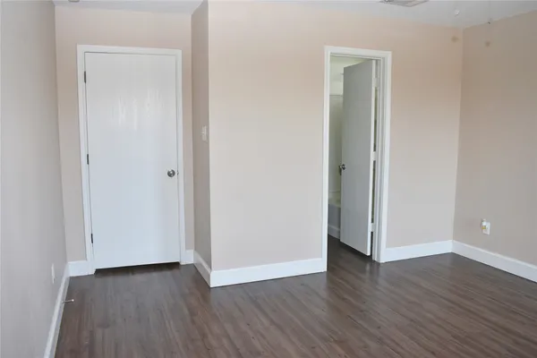 a view of an empty room with wooden floor and closet