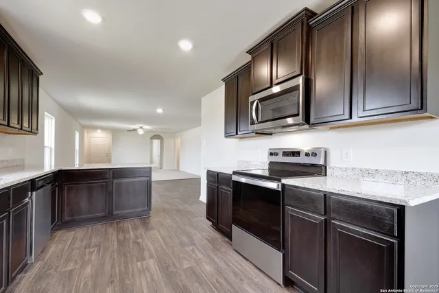 a kitchen with stainless steel appliances granite countertop wooden cabinets a stove top oven a sink and dishwasher
